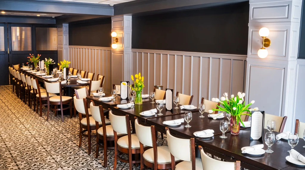 Long tables set for a banquet with tulips and white chairs.