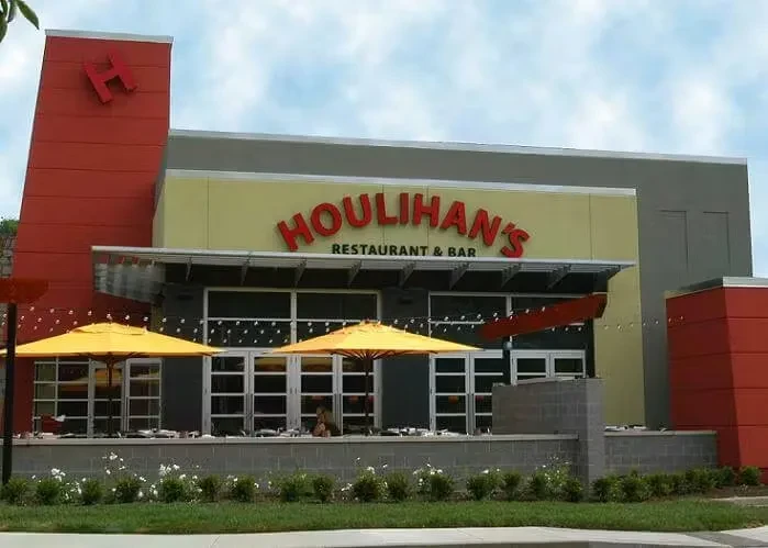 Modern Houlihan's Restaurant exterior, red 'H' logo, patio with yellow umbrellas.