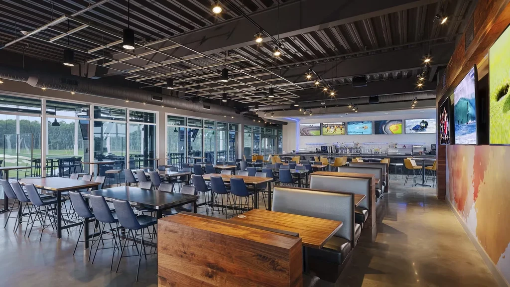 Spacious, modern sports bar interior with golf view and multiple TVs.