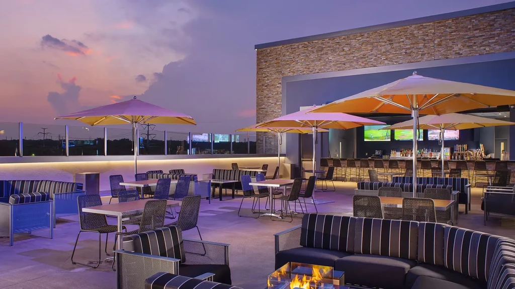 Modern rooftop bar with varied seating and vibrant sunset sky.