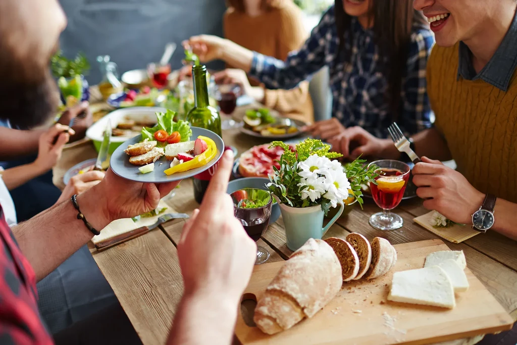 People enjoying a meal together at a long wooden table.