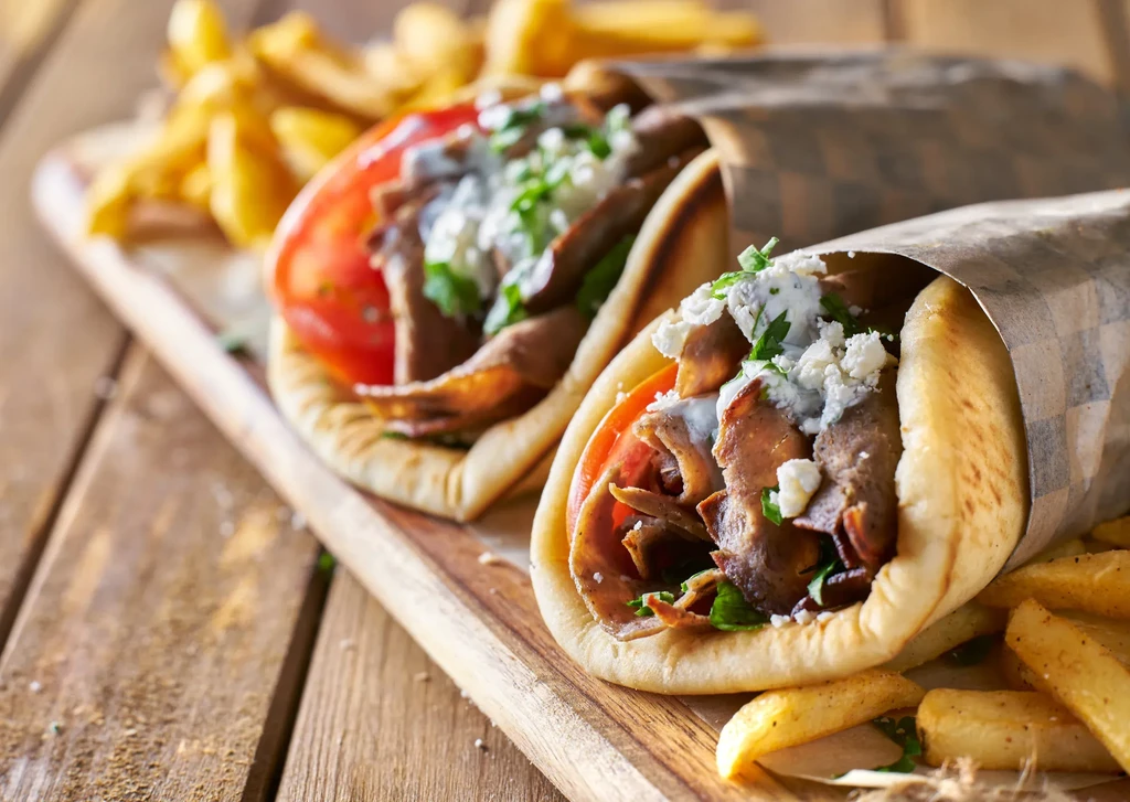 Two loaded gyro sandwiches on pita bread with fries.