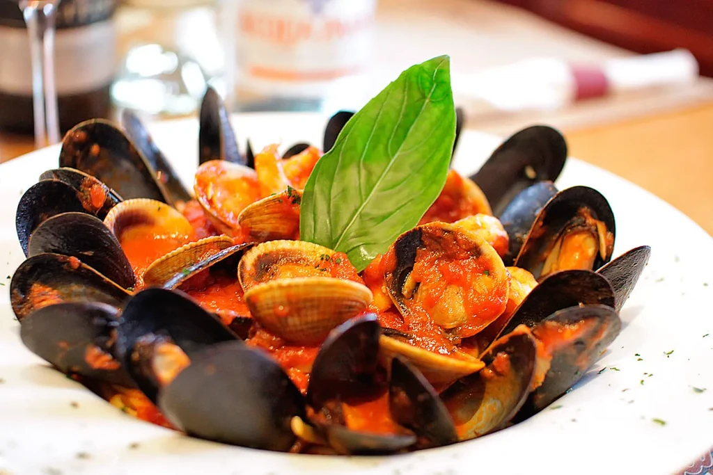 Mussels and clams in a red sauce, garnished with basil.