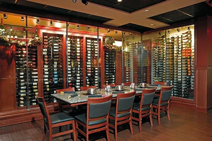 Elegant private dining room with long table and massive wine cellar.