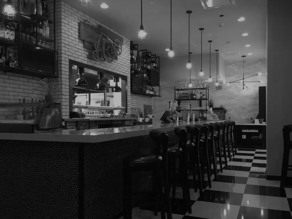 Black and white interior of a modern bar with a checkered floor.