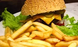 A cheeseburger with pickles, lettuce, and french fries on a white plate.
