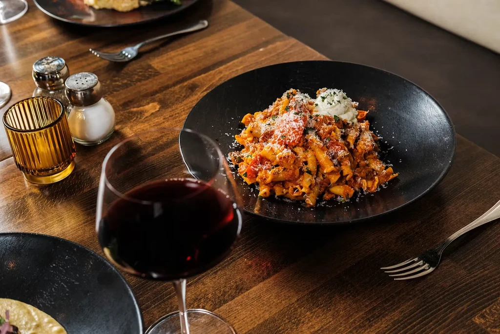Pasta with red sauce, parmesan, and ricotta cheese, with a glass of red wine.