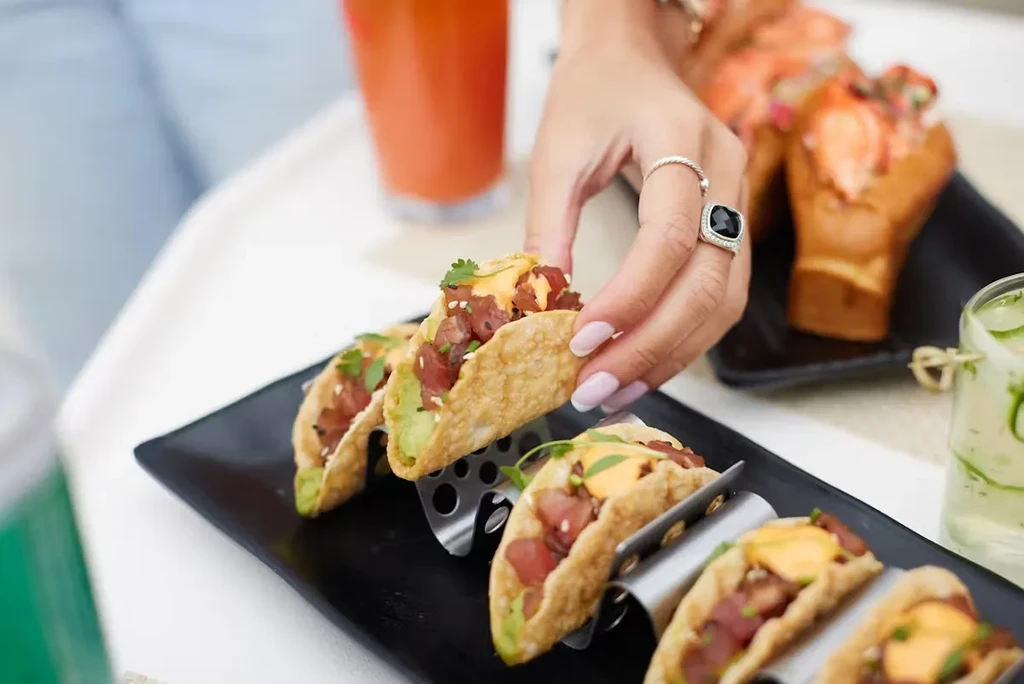 A woman's manicured hand picking up a poke taco.