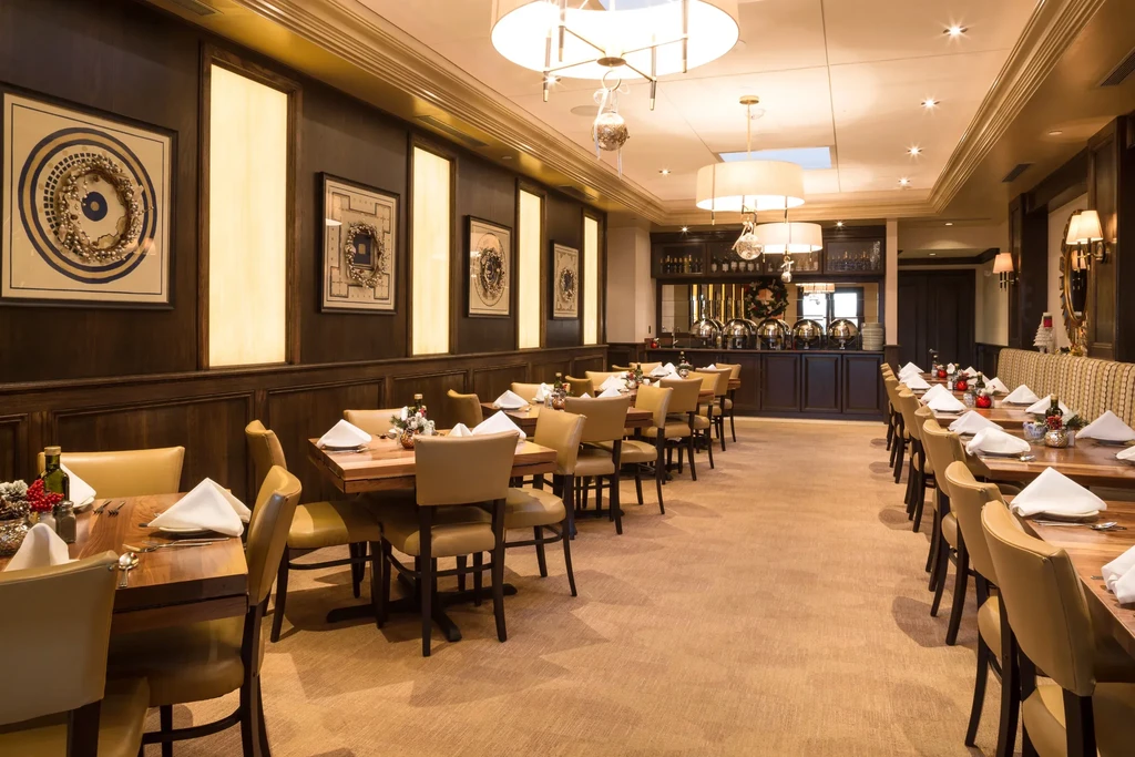 Empty restaurant with tables set and a buffet area at the back.