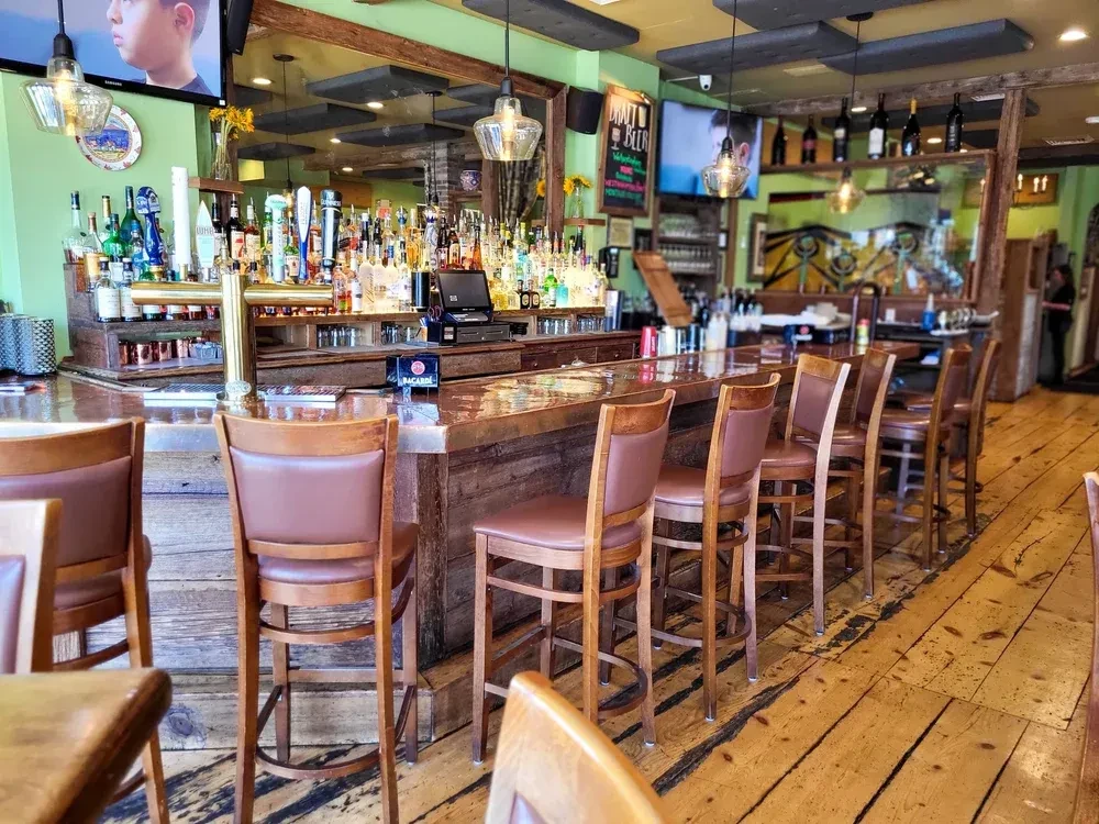 Interior view of an empty bar with many stools and bottles of alcohol.