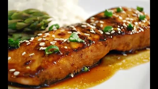 Glazed salmon with sesame seeds, scallions, rice, and asparagus.