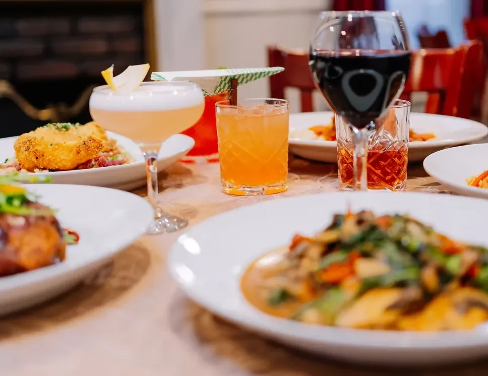 Drinks and food on a dining table with focus on beverages.