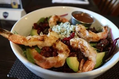 A close-up of a shrimp salad with avocado, cranberries, and blue cheese.