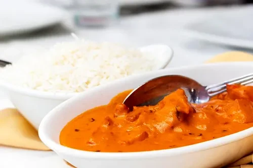Chicken tikka masala and rice in white serving bowls.