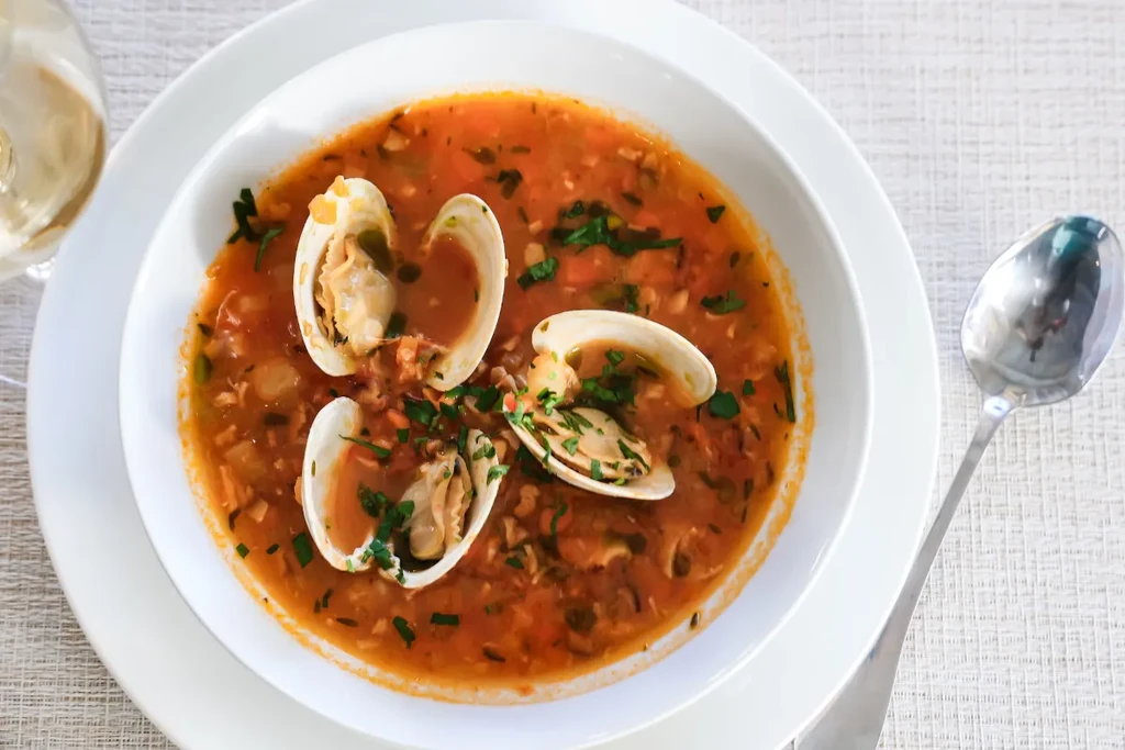 A bowl of clam chowder with white wine and a spoon.