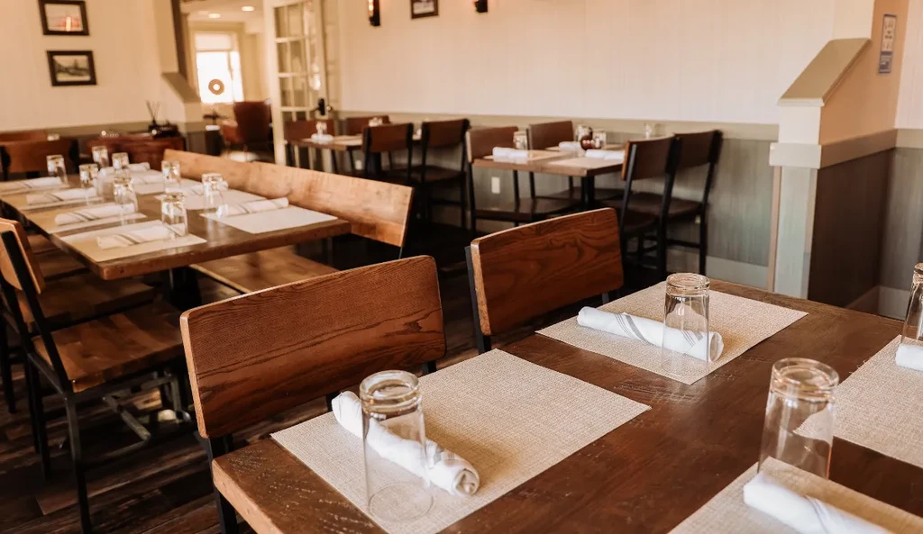 A dining room with multiple wooden tables and chairs set for guests.