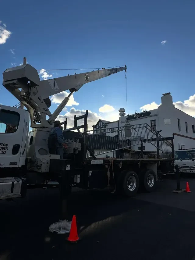 A crane truck with a worker at its controls lifts a sign.
