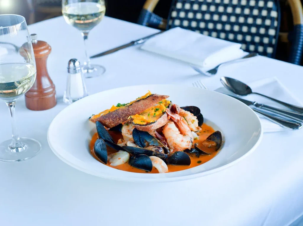 Seafood dish with shrimp, mussels, and toast in a restaurant setting.