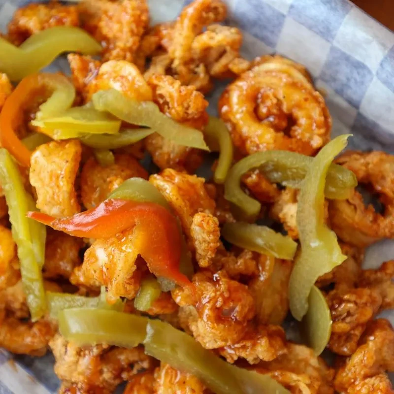 Crispy fried pork rinds with green and red peppers in a basket.
