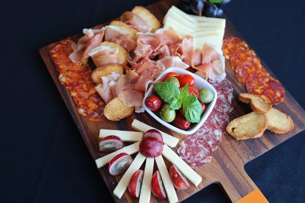 An overhead shot of a charcuterie board on a black background.