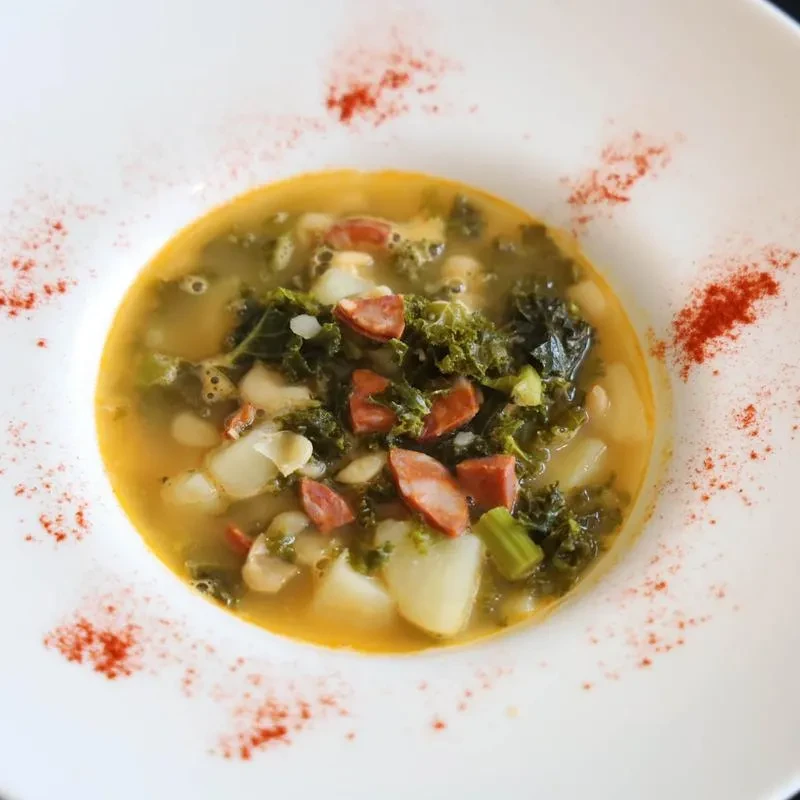 A bowl of caldo verde soup with kale, potatoes, and chorizo.