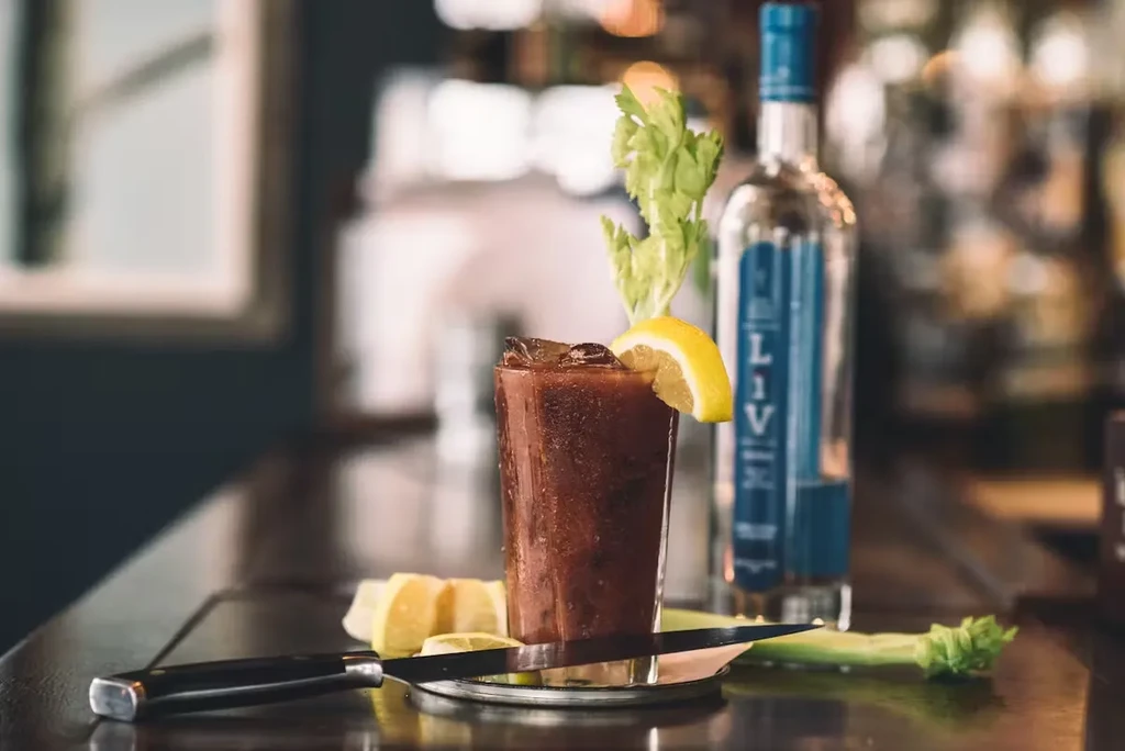 A Bloody Mary with lemon, celery, and vodka on a bar counter.