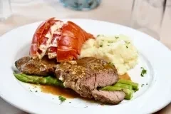 A plate of steak, lobster tail, mashed potatoes, and asparagus.