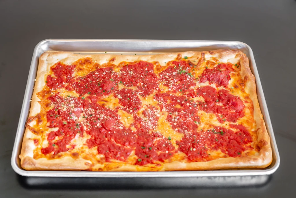 Rectangular pizza with red sauce and cheese in a metal pan.