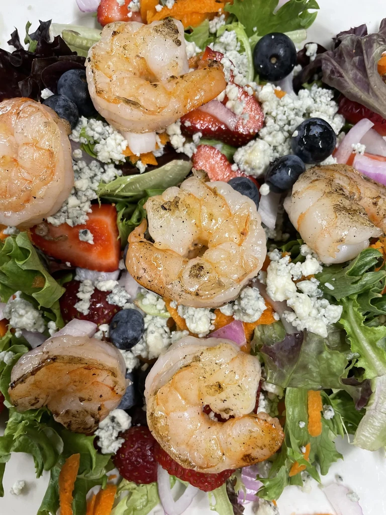 Grilled shrimp salad with mixed greens, berries, and blue cheese.
