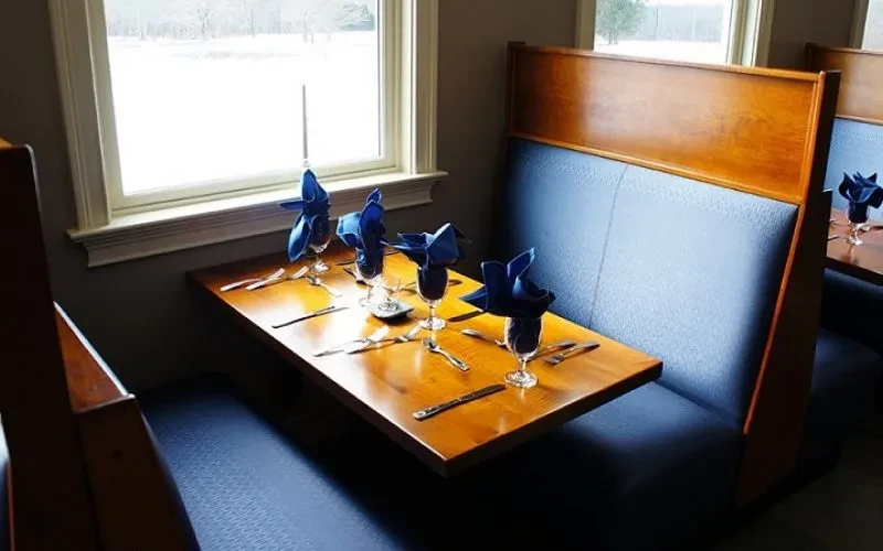 Restaurant booth with wooden table set for four, snowy window background.