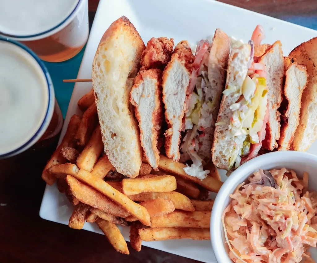 Crispy fried chicken sandwich with fries, coleslaw, and drinks.