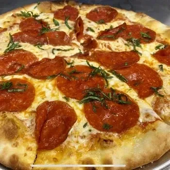 Well-baked pepperoni pizza, melted cheese, curled pepperoni, and basil.