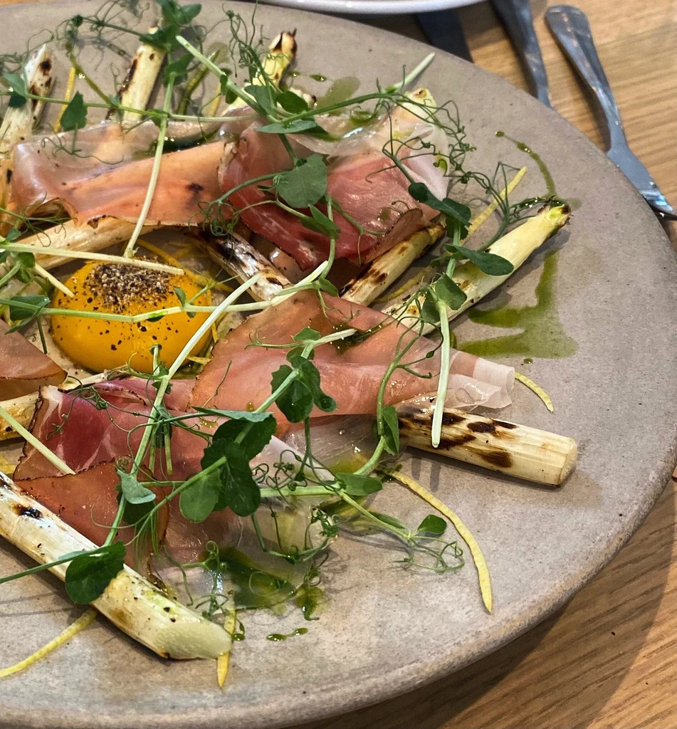 Grilled white asparagus with prosciutto, egg yolk, and microgreens.