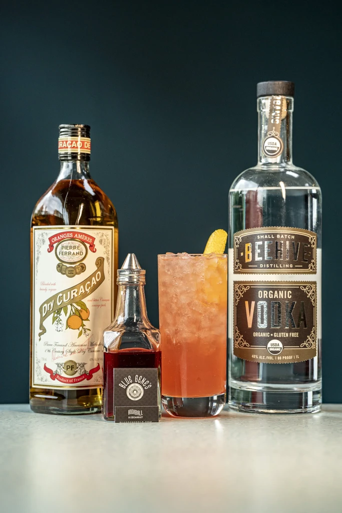 Bottles of Pierre Ferrand, Blue Genes, Beehive Vodka, and a pink cocktail.
