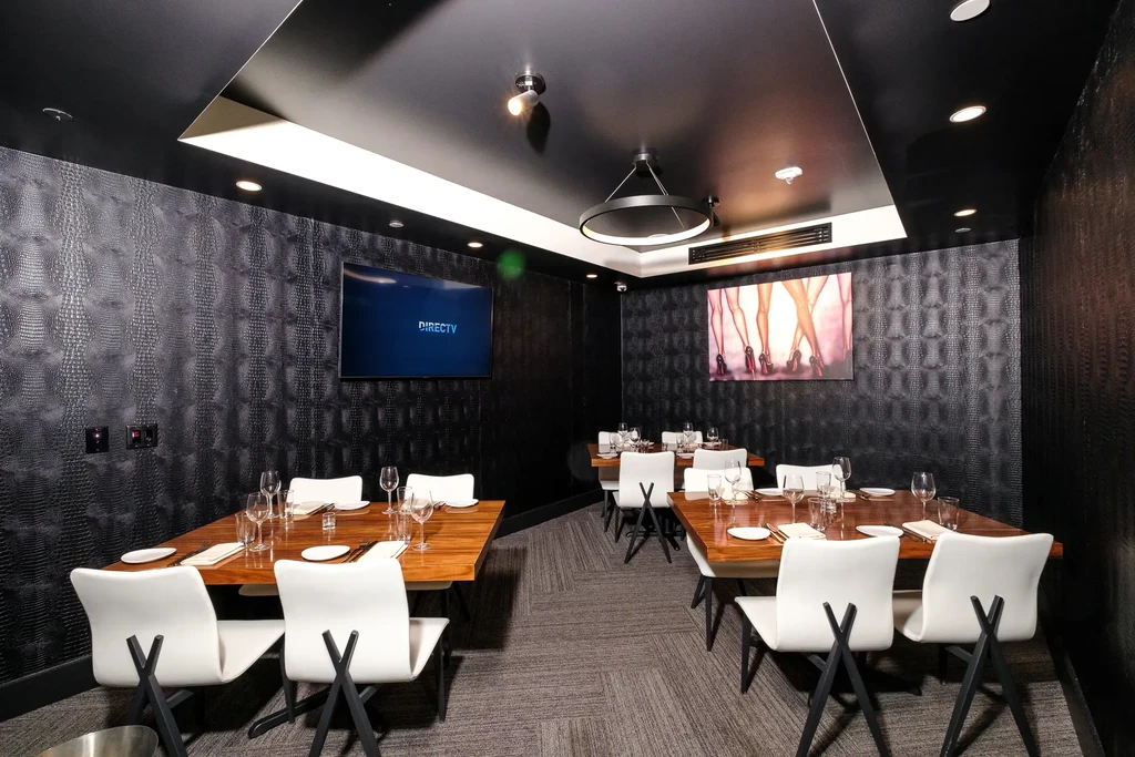 Modern dark dining room with crocodile wallpaper, tables, TV, and artwork.