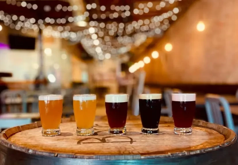 Five beers on a barrel, gradient of colors, warm pub setting.