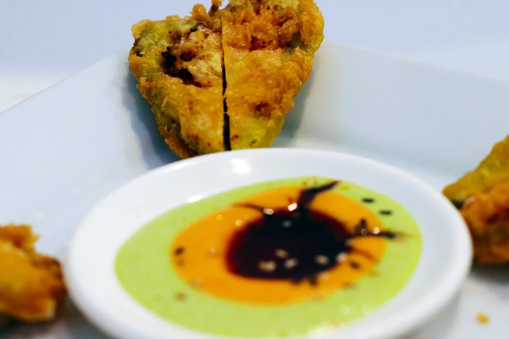 Golden-brown fried vegetable, halved, served with layered dipping sauce.