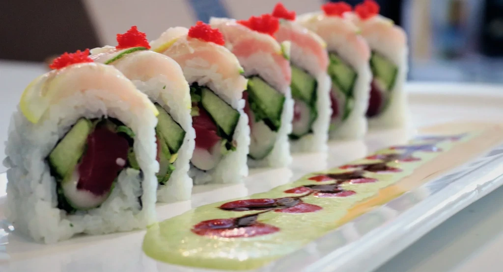 Eight sushi rolls with tuna, cucumber, tobiko, and two sauces.