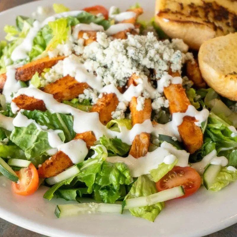 Buffalo chicken salad with blue cheese, lettuce, tomatoes, and toasted bread.