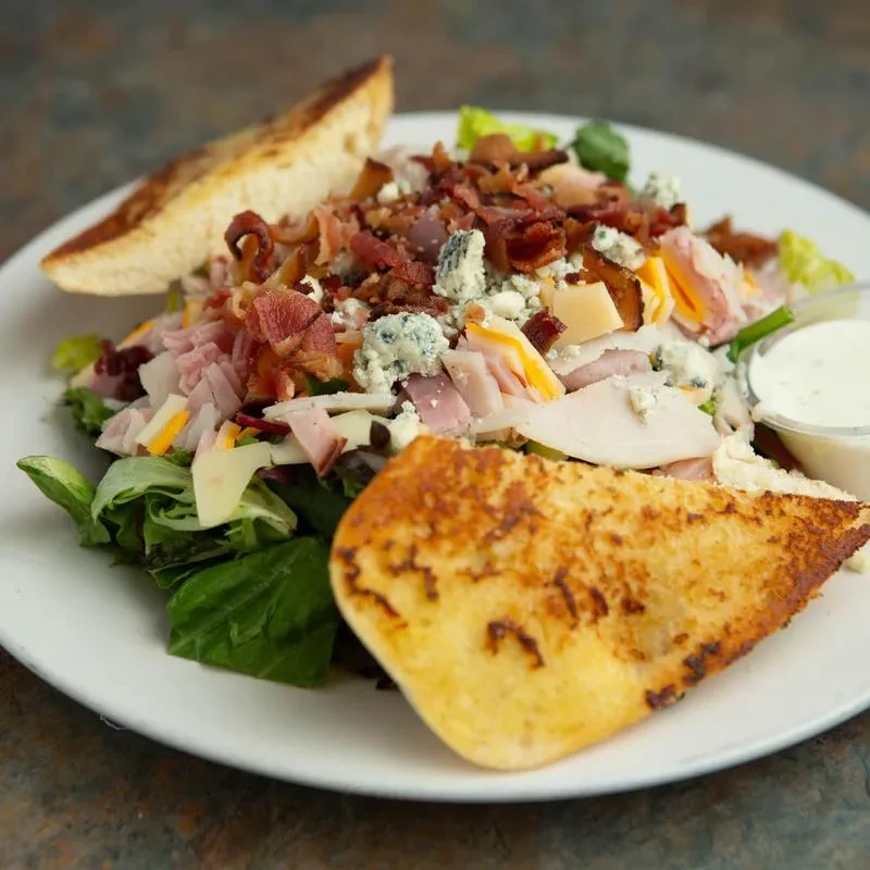 Salad with ham, cheeses, bacon, toasted bread, and creamy dressing.