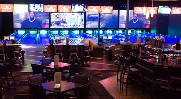 Vibrant neon-lit bowling alley, bar, and dining area.