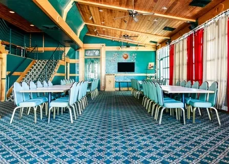 Teal-walled dining space with blue chairs, striped curtains, and wood ceiling.