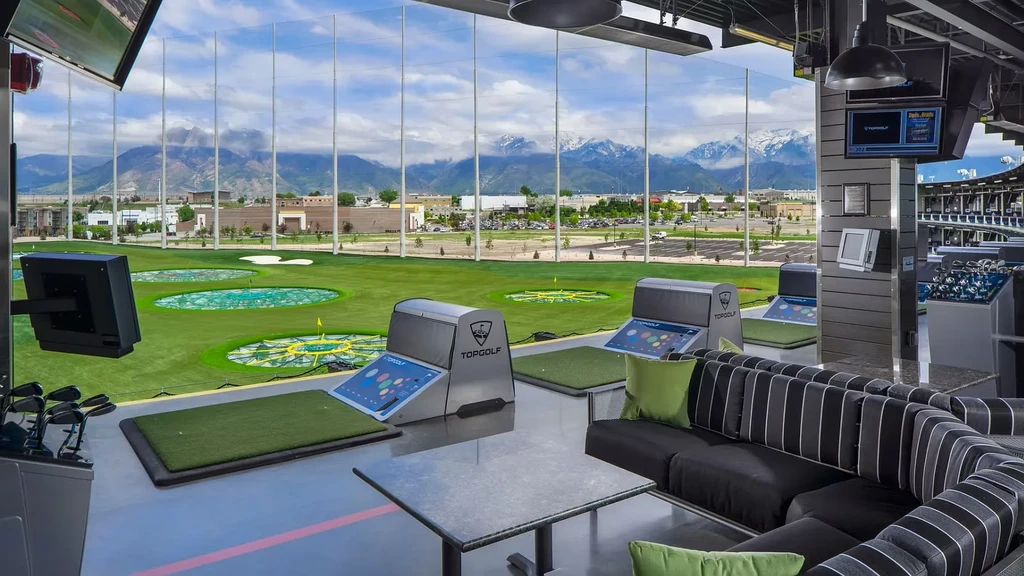 Topgolf interior with hitting bays, lounge seating, and mountain view.