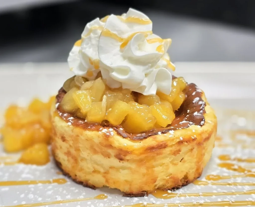 Golden baked dessert with whipped cream, cooked fruit, and caramel.