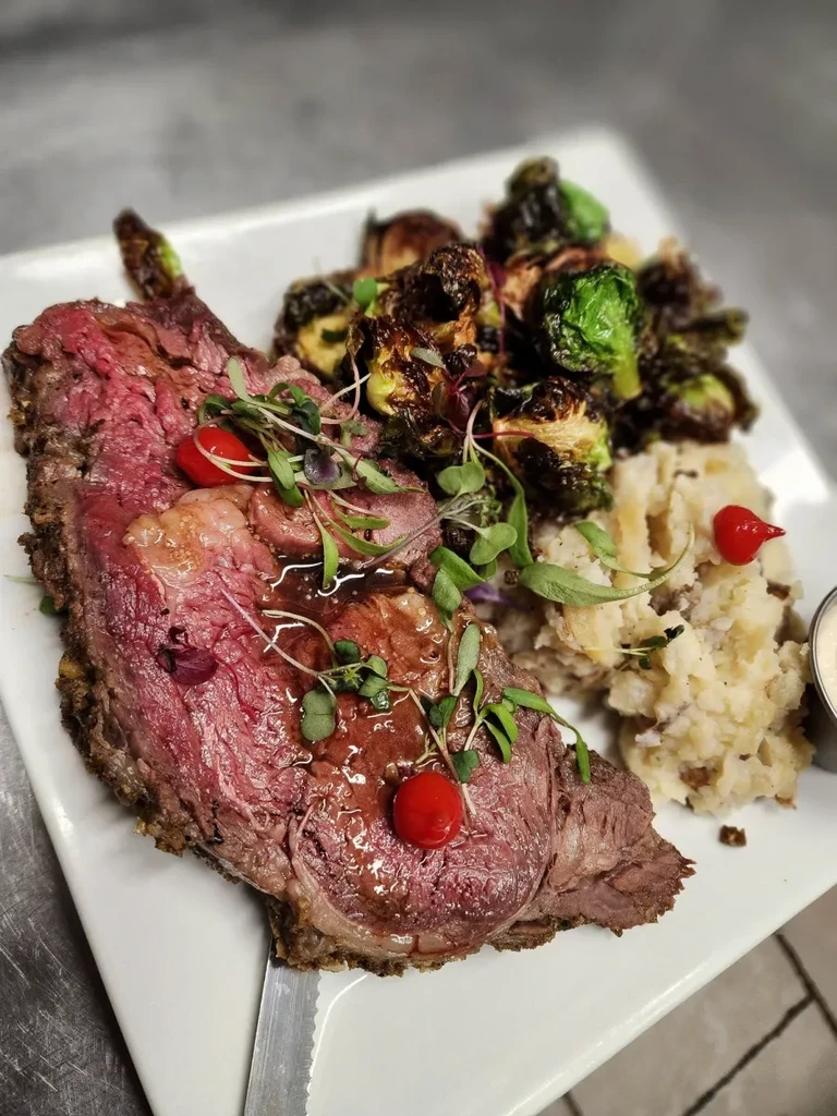Top-down view of medium-rare roast beef with Brussels sprouts and mashed potatoes.