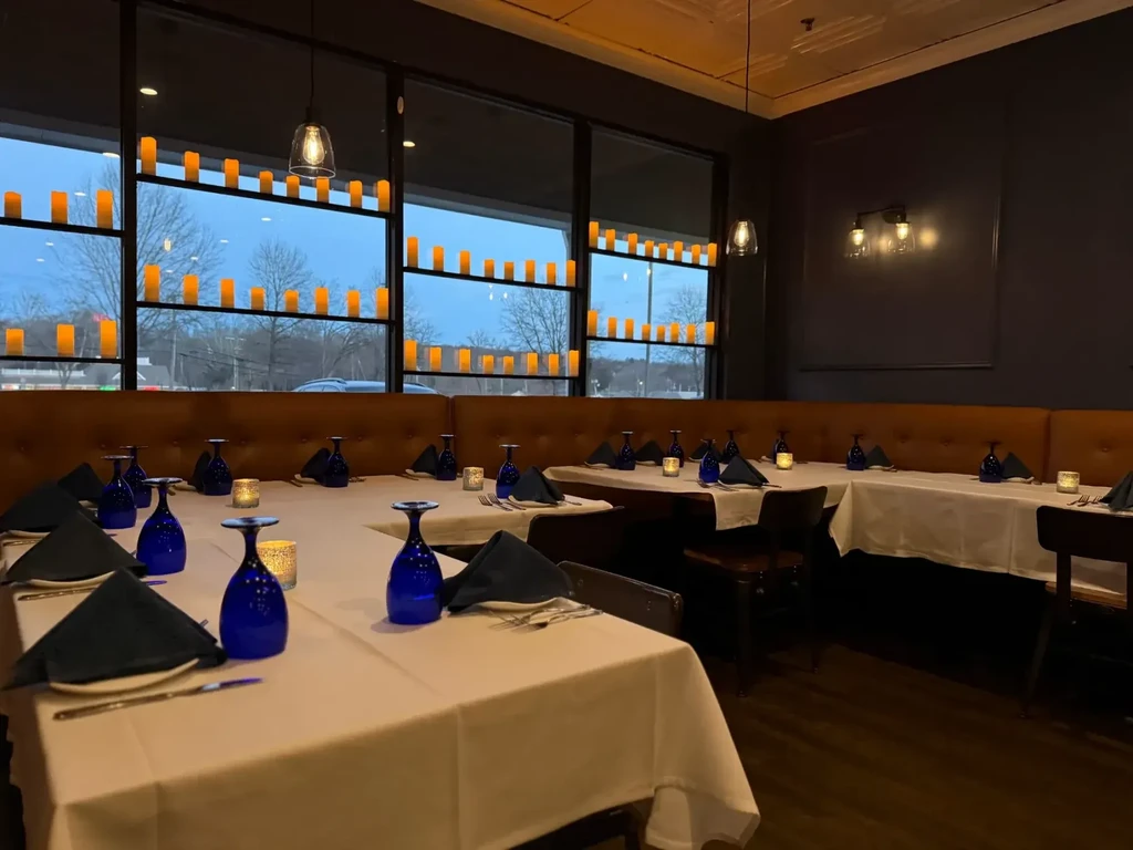 Empty restaurant dining room with U-shaped banquette seating and candlelight.