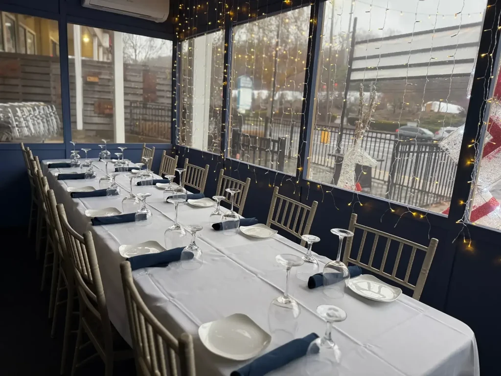 Set dining table with fairy lights in an empty restaurant sunroom.