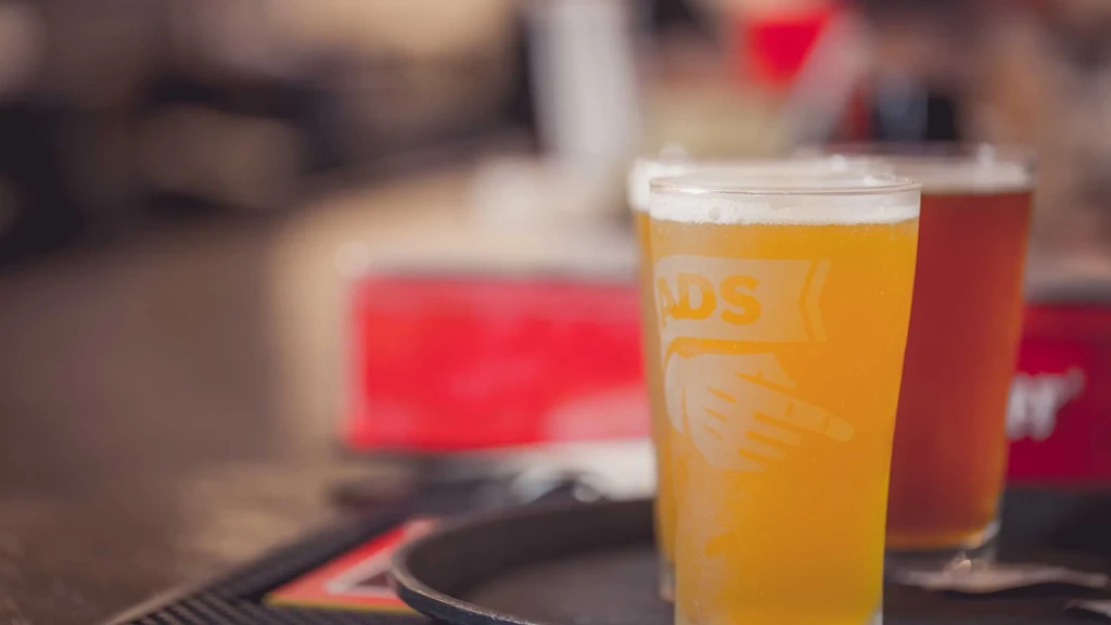 Frosted glass of golden beer with ADS logo, darker beer behind.
