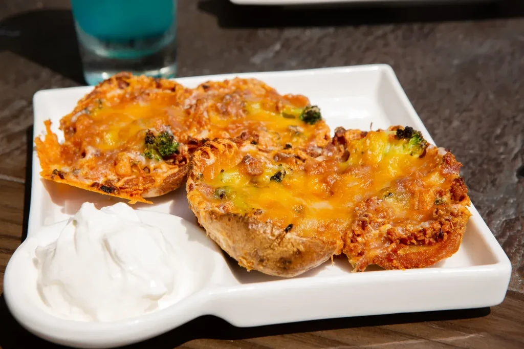 Baked potato halves with cheese, broccoli, bacon, and sour cream.