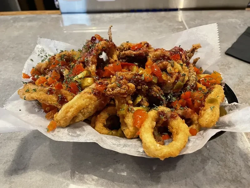 Crispy fried calamari with peppers, dark sauce, and green herbs.